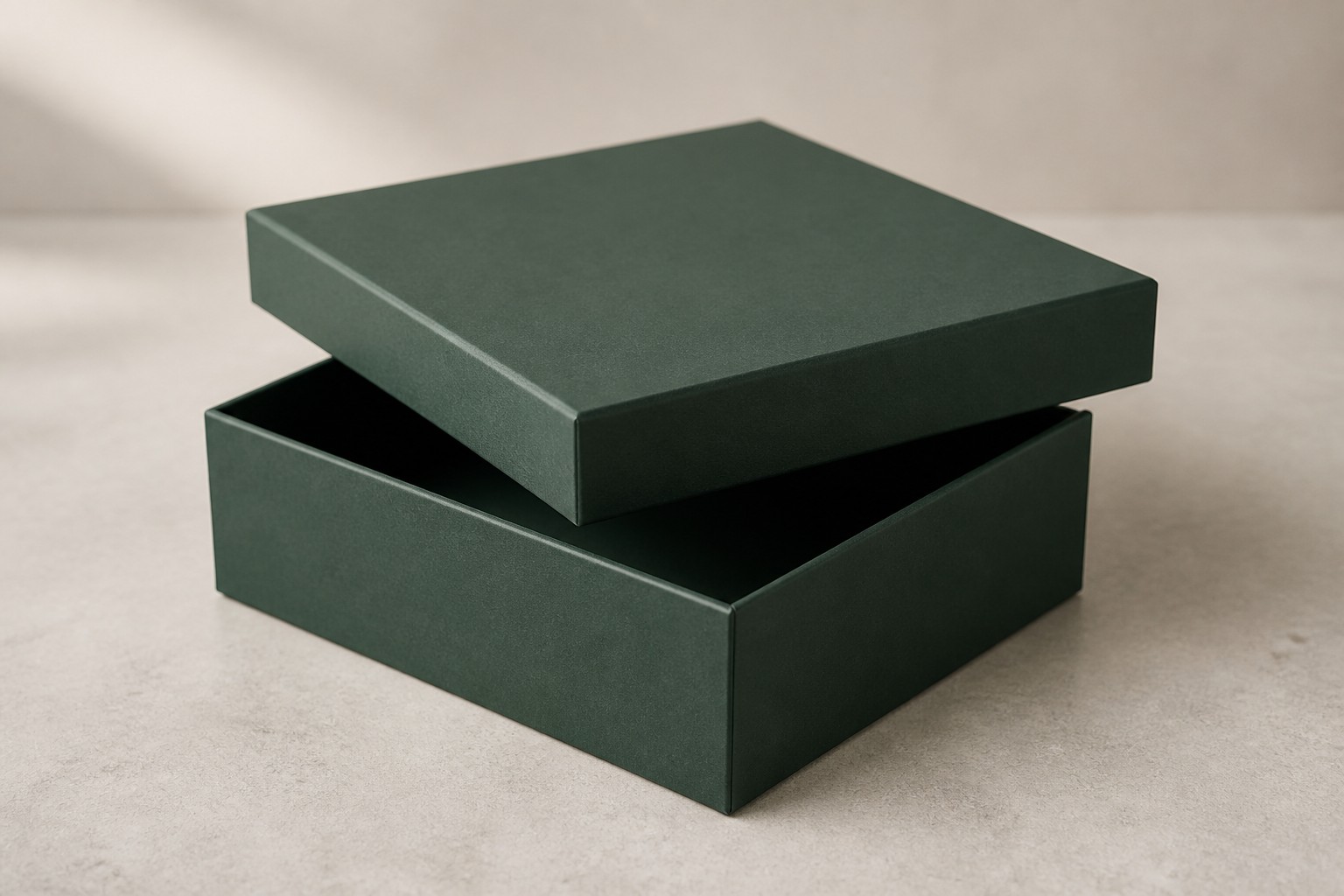A forest-green rigid gift box with its lid lifted slightly above the base.